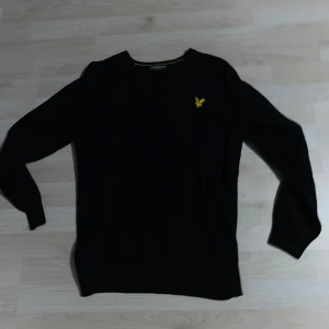 Svart ulltröja från Lyle & Scott - Säljer en klassisk svart långärmad tröja från Lyle & Scott med gul broderad logga på bröstet. Tröjan är i ull och har ribbade muddar vid ärmslut och nederkant. Perfekt för kyligare dagar. Material är Ull. Originell storlek XL, sitter som en M. Skriv gärna vid minsta fråga, pris kan diskuteras.