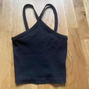 Svart ribbad linnetopp - Svart ribbad linnetopp. Perfekt för varma dagar eller som lager under en skjorta. Enkel och stilren design som passar till mycket.