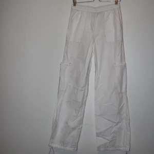 Vita cargopants med raka ben - Säljer ett par vita cargopants med raka ben och stora fickor på sidorna. Jätte najs inför varmare dagar då materialet är lite tunnare. Helt oanvända orginellt köpa på asos. 