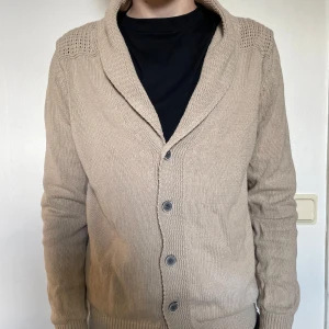 Beige cardigan från Massimo Dutti - Säljer en beige cardigan från Massimo Dutti med knappar framtill och snygga mockadetaljer på armbågarna. Storlek S. Skriv om ni har frågor 