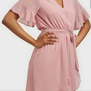 Rosa omlottklänning med volangärm - Söt rosa omlottklänning med volangärmar och knytskärp i midjan. Klänningen har v-ringning och är tillverkad i ett lätt, flowy material som ger en luftig känsla. Perfekt för varma dagar och somriga tillfällen. Nyskick. Stl ca 38-40.