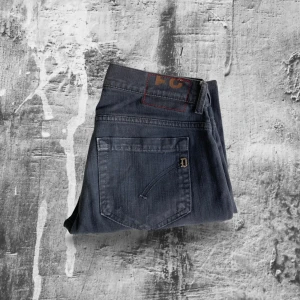 Svarta Dondup jeans - Svarta Dondup jeans med rivningar i modell George. Perfekt om man vill ha ett par relaxed jeans med stil och bra passform.