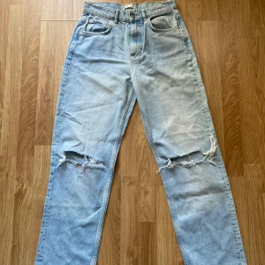 Baggy jeans med hål från Gina  - Super snygga jeans som sitter lite baggy. Har två hål ungefär vid knäna. Är i stolek 38/M. Har måtten 47cm över midjan, ca 27cm från benskärningen till midjan och ca 109 cm i ben längd. Hör av er vid frågor!💕