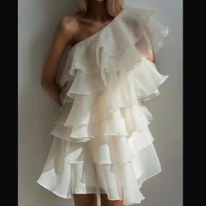 Vit volangklänning med oneshoulder - Superfin vit kortklänning med flera lager volanger och oneshoulder-design. Klänningen har en luftig  känsla, perfekt för sommarens tillfällen.  Bara att skriva vid funderingar🌸💗
