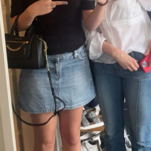 Blå jeanskjol från Levi's - Snygg blå jeanskjol från Levi's med klassisk femficksdesign och slitna detaljer. Kjolen har en knapp och dragkedja framtill samt bälteshällor. Perfekt för en avslappnad stil.