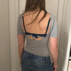 Grå body med djup rygg - Säljer en enkel och stilren grå body med korta ärmar och djup urringning i ryggen. Perfekt att styla med jeans eller kjol för en clean look. Mjuk och stretchig i materialet.