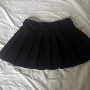 Svart plisserad kjol från H&M - Säljer en svart plisserad kjol från H&M med bred midjeresår och klassisk kort modell. Kjolen går att justera vid midjan. Använd ett fåtal gånger. Säljer då inte är min stil längre.💗