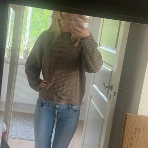 Brun stickad tröja från H&M - Mysig brun stickad tröja från H&M med rund halsringning och långa ärmar. Perfekt för kyligare dagar och enkel att matcha med jeans eller kjol. Klassisk modell med ribbade muddar vid ärmslut och nederkant.