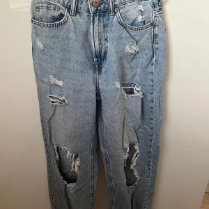 Ljusblåa loose straight high waist - Ljusblå jeans med loose fit och raka ben. Hög midja och flera slitningar och hål framtill. Klassisk femficksmodell i bomullsdenim. 