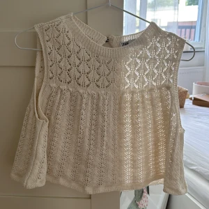 Stickad topp från Zara - Supersöt ärmlös topp från Zara i ljusbeige virkad material. Toppen har ett vackert hålmönster, rund halsringning och knapp i nacken. <3