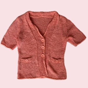 Korallorange stickad kofta från Oui - Kortärmad kofta i korallorange från Oui, stickad i bomull. Djup v-ringning, fyra knappar framtill och två små fickor med knappdetalj.  Köpte på VINTED men den passade inte, men den har inga tecken på användning 🩷