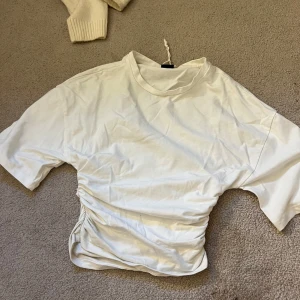 Vit t-shirt med snörning Gina Tricot - Vit t-shirt från Gina Tricot i storlek XXS. Modellen har korta ärmar, rund halsringning och snygg snörningsdetalj på ena sidan som ger en rynkad effekt. Tillverkad i mjuk bomull, perfekt för en clean och trendig look. Jättefin.