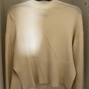 Beige stickad tröja från Gina Tricot - Supermjuk beige stickad tröja från Gina Tricot i storlek S. Tröjan har ribbade muddar och nederkant, rund halsringning och en loose fit som ger en chill vibe. Perfekt att slänga på sig när det är lite kyligt ute.