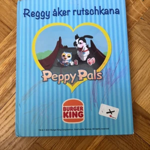 Reggy åker rutschkana - En charmig bilderbok om hunden Reggy som vågar prova nya saker på lekplatsen. Med färgglada illustrationer och frågor att diskutera, passar den perfekt för unga som vill läsa om vänskap, mod och känslor.