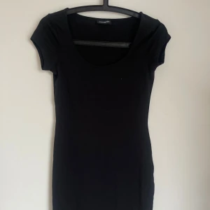 Svart kort klänning från Even&Odd - Enkel och stilren svart kortklänning från Even&Odd med rundad urringning och korta ärmar. Klänningen är figurnära och gjord i mjuk bomull, perfekt för en clean och klassisk look.