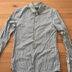 Randig skjorta från H&M, storlek S - Snygg skjorta från H&M i storlek S med svartvita ränder. Klassisk krage, långa ärmar och knäppning framtill. Skjortan är i tunn bomull, perfekt för en clean och stilren look. Passar dig som gillar enkel men trendig stil.