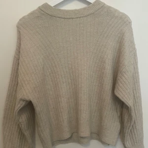 Beige ribbstickad tröja från H&M - Beige ribbstickad tröja från H&M i storlek S. Tröjan har en avslappnad passform med rund halsringning och långa ärmar. Perfekt för lager-på-lager och enkel att matcha med jeans eller kjol. Har använt några gånger men tyvvär har den blivit för liten för mig. Väldigt skönt material. Går att pruta 