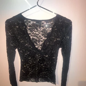 Svart spetsblus från Gina Tricot XS - Supersnygg svart långärmad blus i spets från Gina Tricot. Transparent och figurnära modell med v-ringning och blommigt spetsmönster. Perfekt att styla med jeans eller kjol för en trendig look.