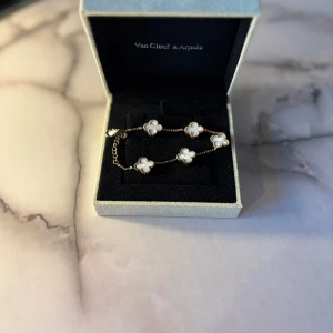 Van Cleef-smycke – Vitt - Elegant och tidlöst smycke med vit detalj. Ger en lyxig, ren känsla som passar perfekt till både ljusa och mörka outfits.