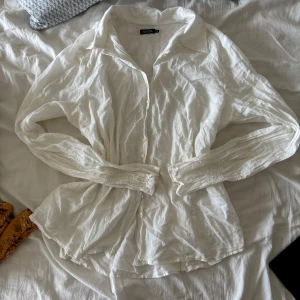Vit blus i linne från Sisters Point - Drömmig vit skjortblus i tunn bomull med linnekänsla från Sisters Point. Smockade ärmslut, klassisk krage, knappar fram och lätt transparent. Den perfekta sommarblusen – avslappnad, luftig och stilren 💫 Funkar lika bra till jeans som till kjol!  📏 Storlek 44 (passar M/L) 🧼 Mycket fint skick 📬 Skickas snabbt