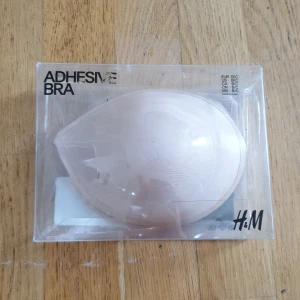 Beige självhäftande bh från H&M - Självhäftande bh i beige från H&M, perfekt för outfits där du vill slippa synliga axelband. Bh:n är slät och formad för att ge stöd och en naturlig look under kläder. Passar storlek B/C och är enkel att använda till axelbandslösa eller öppna toppar.
