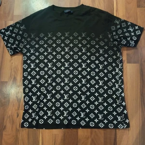 Svart Louis Vuitton t-shirt XL - Svart t-shirt från Louis Vuitton i storlek XL med ikoniskt monogrammönster i vitt över hela plagget. Klassisk passform med korta ärmar och rund hals. Tillverkad i 100% bomull för en skön känsla och snygg look. Pris kan diskuteras 