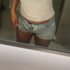 Stradivarius jeans shorts  - Säljer ett par riktigt snygga lågmidjade jeansshorts i ljusblå denim. De har slitna detaljer och fransig kant nedtill för en mer vintage stil. Perfekta för varma sommardagar.