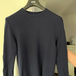 Mörkblå merinoullströja Stenströms L - Säljer en stilren mörkblå stickad tröja från Stenströms i 100% merinoull. Tröjan har rund halsringning och lång ärm, perfekt för dig som gillar klassisk och clean look. Passar dig som vill ha en mjuk och skön tröja med premiumkänsla. Passar även M