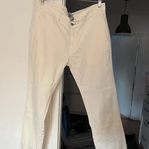 Beiga chinos från NN07, storlek 36/34 - Snygga beiga chinos från NN07 med klassisk rak passform. Byxorna har snörning i midjan, två sidofickor fram och två bakfickor. Tillverkade i mjuk bomull som känns skön mot huden. Perfekta för en clean och stilren look.