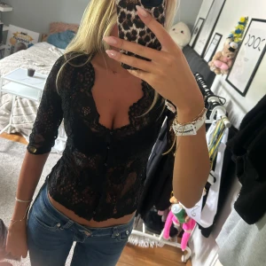 Svart spetsblus med knappar - Säljer en svart spets topp med knappar framtill. Finns en defekt då två knappar saknas vilket inte syns när man knäpper dem andra