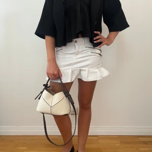 Vit jeanskjol med volang och dragkedjor - Supersnygg vit kort jeanskjol från esprit med volangkant nertill och coola dragkedjor framtill. Kjolen har klassiska fickor både fram och bak samt bälteshällor. Perfekt för dig som vill ha en fräsch och trendig look i sommar!