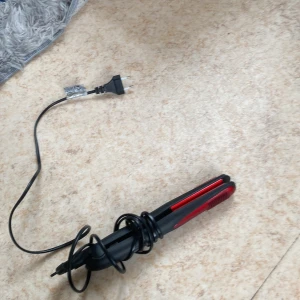 Svart och röd plattång - En smidig plattång i svart och rött med sladd och stickkontakt. Perfekt för att styla håret rakt eller skapa mjuka vågor. Ergonomiskt handtag och värmeplattor i keramiskt material för jämn värmefördelning.