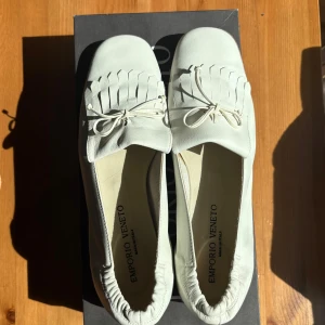 Vintage Emporio Veneto loafers – kalvskinn i cremevit, strl 36,5 -  	•	👞 Vintage-loafers från Emporio Veneto 	•	🤍 cremevita i mjukt kalvskinn 	•	🎀 Frans- och knytdetalj framtill 	•	🇮🇹 Tillverkade i Italien, hög kvalitet 	•	✨ Felfria i ovandelen, sparsamt använda 	•	👗 Passar både vardag och dressade outfits  Pris: 399 SEK