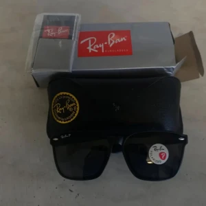 Svarta Ray-Ban Wayfarer solglasögon - Klassiska svarta Ray-Ban Wayfarer solglasögon med polariserade linser. Snygg, tidlös design med rektangulär form och diskreta silvriga detaljer vid bågarna. Kommer med originalfodral och Ray-Ban-förpackning.