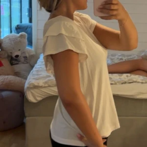 Vit volangärmad topp från Kappahl - Supersöt vit topp från Kappahl med v-ringning och korta ärmar med dubbla volanger. Perfekt för dig som gillar en enkel men ändå trendig look. Använd 1 gång. Köpt på Kappahl och är k storlek S💞