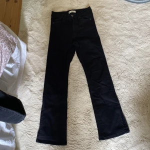 Svarta bootcut jeans med slits från Gina Tricot i Petite modell - Svarta jeans från Gina Tricot med bootcut-modell och snygga slitsar nertill på benen. Klassisk femficksdesign och mellan hög midja. Jeansen är i ett stretchigt bomullsmaterial som sitter bekvämt och ger en clean look. Är använd fåtal gånger. Tyvärr vuxit ur de. De är i Petite jeans och sitter jättefint på! 💕💕