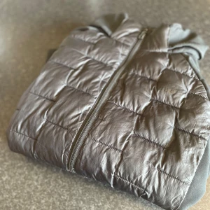 Grå quiltad jacka från Everest - Snygg grå quiltad jacka från Everest med dragkedja framtill. Jackan har en sportig look med rutmönstrad framsida och mjuka ärmar. Perfekt för kyliga dagar när du vill hålla stilen enkel och clean.    Obs!!!⚠️på högra sidan har Jack fickan gått sönder i drag kedjan men annars inne fickor och allt finns 
