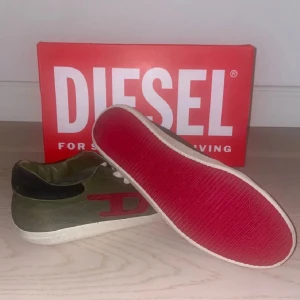 Diesel skor - Säljer ett par gröna sneakers från Diesel med röda detaljer på sidan och vita snören. Skorna har en röd sula och är perfekta för en avslappnad stil.sulan är lite trasig men inget som märks.boxen ingår inte!