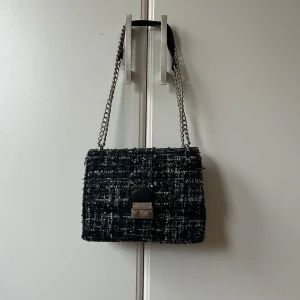 Svart och vit axelväska med kedja - Snygg axelväska i svart, silver, blått med ett rutigt mönster. 