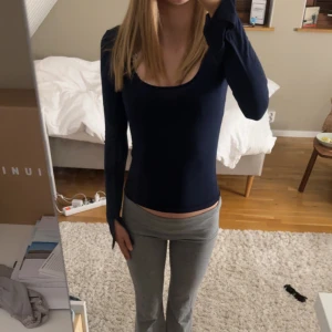 Mörkblå långärmad topp - Säljer en stilren mörkblå långärmad topp med djup urringning. Perfekt för en enkel och snygg look. Passar bra till både jeans och kjol. Har slit i ärmarna. 