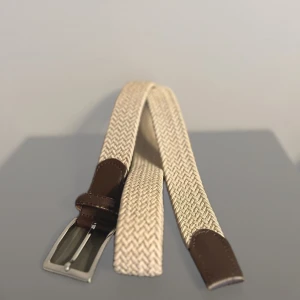 Flätat bälte/skärp - Beige  - Snyggt beige flätat bälte med bruna skinn-detaljer och silverfärgat spänne. Hör gärna av dig vid fler frågor eller om du vill diskutera pris.   Köp 2 varor och få 15 % rabatt, 3 varor ger 20 % rabatt, och vid 5 varor får du hela 30 % rabatt. 