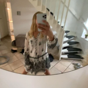 Vit och svart mönstrad klänning från zara  - Säljer en vit klänning med svart mönster och långa ärmar. Klänningen har en avslappnad passform och  säljs pågrund av att den inte blir använd och är bara använd en gång på midsommar. Nypris från zara ligger på 500kr