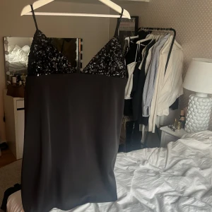 Svart paljettklänning från Zara - Snygg svart klänning från Zara med paljetter upptill och smala axelband. Perfekt för en kväll ute eller en speciell tillställning. Klänningen har en elegant och stilren design. Storlek XL men skulle säga att den sitter som en M/L. 
