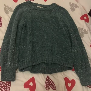 Grön glittrig tröja från H&M - Säljer en snygg grön glittrig tröja från H&M. Tröjan har långa ärmar och en ribbad kant vid ärmslut och nederkant. Hör av dig vid intresse 