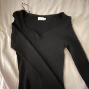 Svart ribbad topp från Stockh LM Studio - Snygg svart ribbad topp från Stockh LM Studio med v-ringning. Perfekt för en stilren look. Toppen har en elegant passform och är tillverkad i ett mjukt material.