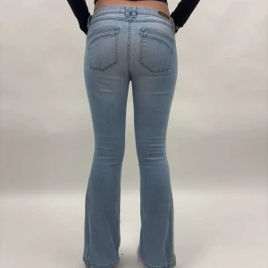 Ljusblå lågmidjade jeans - Blå omsydda jeans från skinny till bootcut. Det är lite korta för modellen så de ger inte ens helhetsbild hur jeansen egentligen skulle ha suttit. Det är i storlek W28/L30