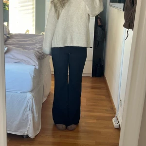 Svarta bootcut kostymbyxor - Snygga svarta bootcut byxor med Low/medelhög midja. Perfekta för en stilren look. Byxorna har en klassisk design med en lätt utsvängd passform och pressveck som ger en modern touch. Väldigt fint skick. Jag är 160 som referens!