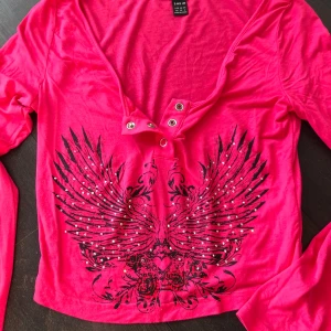 Rosa långärmad topp med tryck - Snygg rosa långärmad topp från Shein med ett coolt tryck av svarta vingar och gnistrande detaljer framtill. Använd 1-2 gånger. Alla stenar sitter kvar 🥰