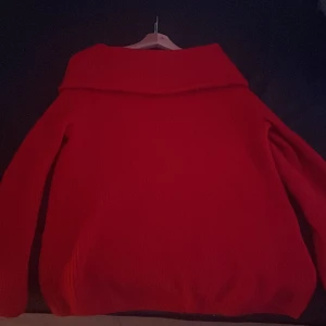 Röd stickad tröja H&M - Säljer en mysig röd stickad tröja med bred krage. Perfekt för kyliga dagar och ger en härlig färgklick till garderoben. Tröjan har långa ärmar och en avslappnad passform.