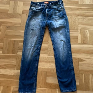 Blå slim jeans från Jack & Jones - Snygga blå slim jeans från Jack & Jones med en sliten look. De har en klassisk femficksdesign och är perfekta för en avslappnad stil. Passar bra till både sneakers och kängor.